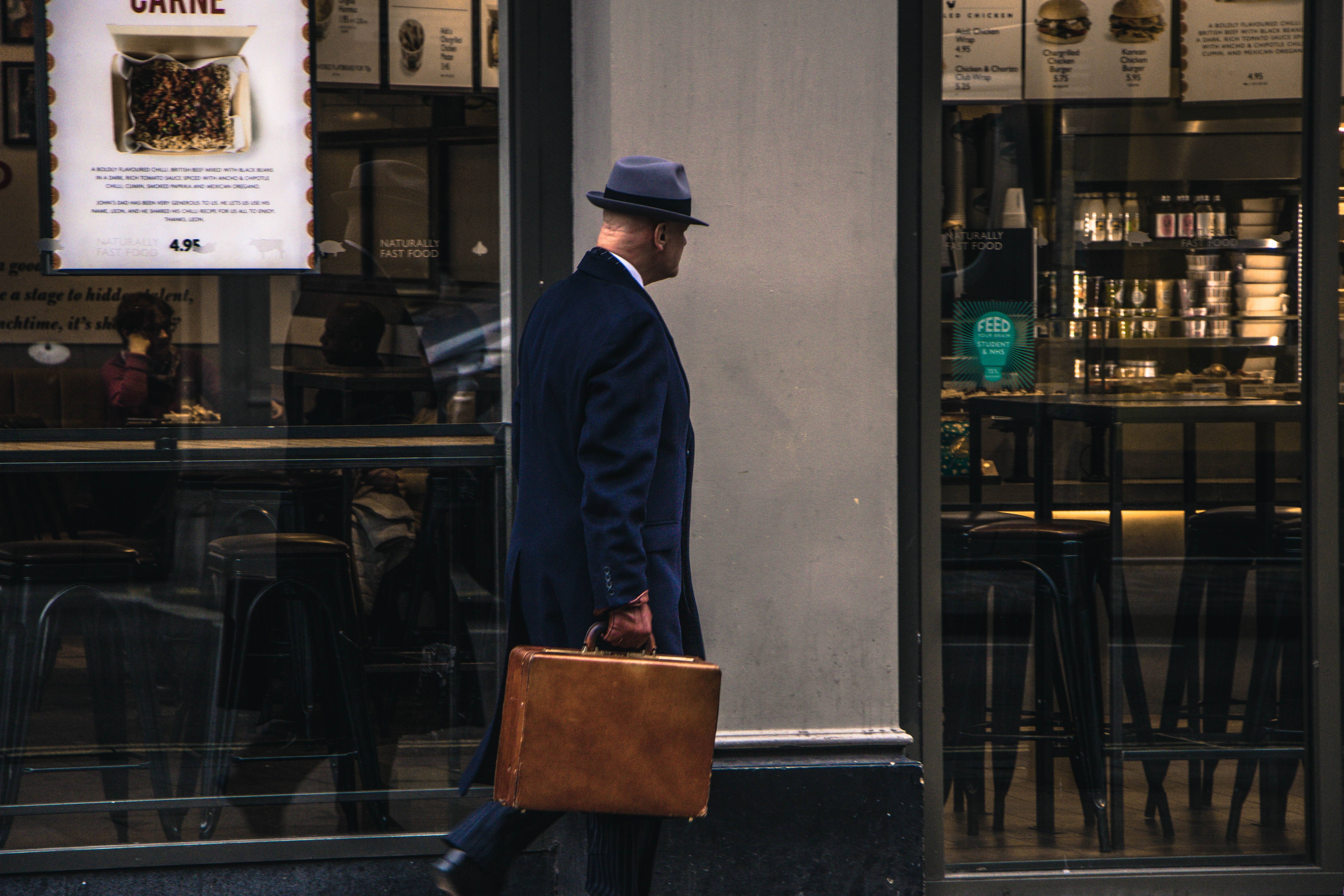 Suspicious looking man walking with suitcase on the street